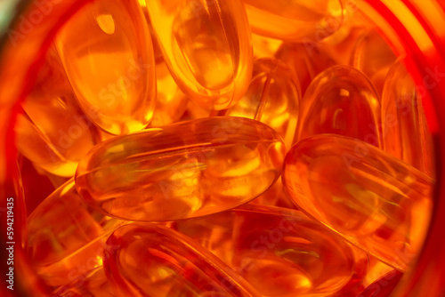 lots of yellow gelatin capsules on a red background. omega viramins, close-up, macro