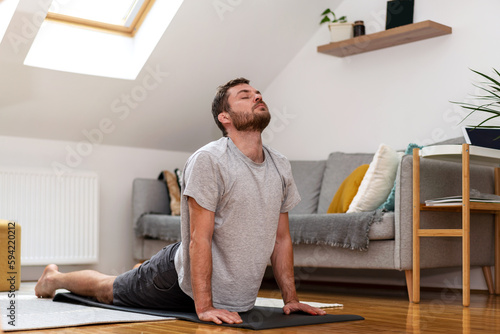 Tablou canvas Wrestler man with broken ears doing stretching exercise on yoga mat at home