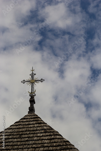 old wooden church against the blue sky in Ukraine, wooden roof with a cross