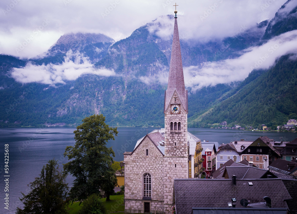Panorama view of a church in Hallstatt city with lake in Hallstatt, Austria on a rainy day with clouds