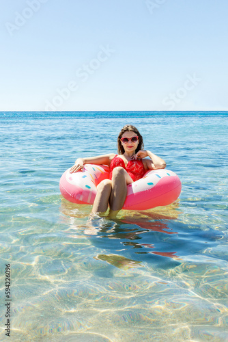 Beautiful young woman with inflatable donut in the sea