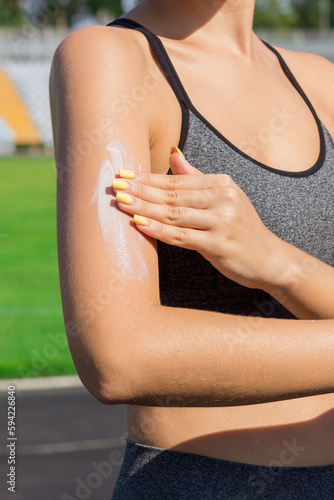 Woman spraying sunscreen cream on skin before run. Sports and healthy concept