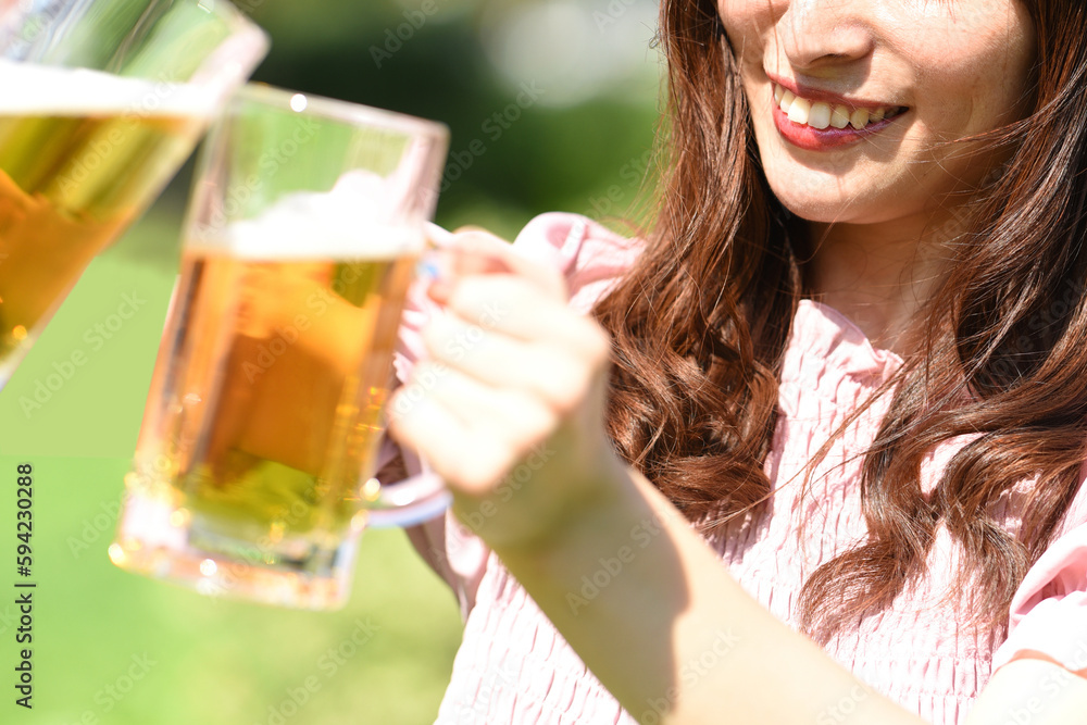 外でビールを持ちながら乾杯をする女性 外でビールを持ちながら乾杯をする女性