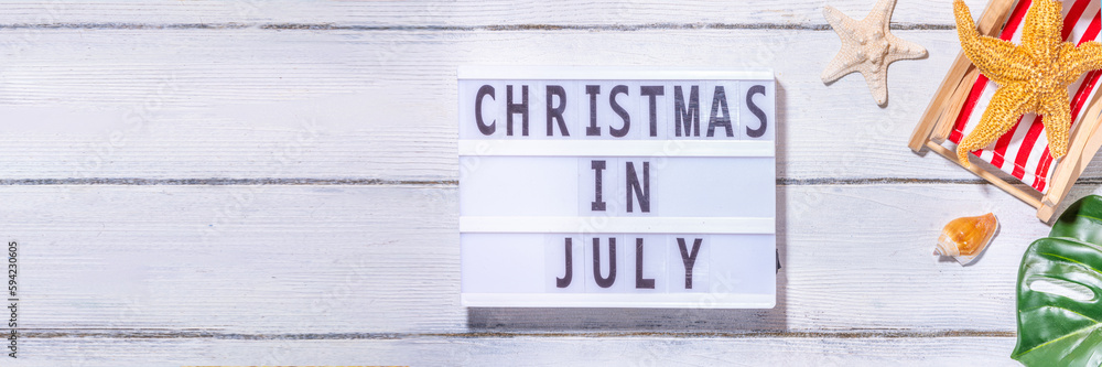 Christmas in July summer holiday or sale background. Summer vacation accessories, seashells, Starfish, lounge chair with Santa hat, tropical leaves. Getaway during winter holiday, top view copy space Christmas in July summer holiday or sale background. Summer vacation accessories, seashells, Starfish, lounge chair with Santa hat, tropical leaves. Getaway during winter holiday, top view copy space