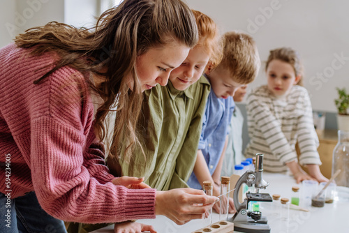 Young teacher doing chemistry experiment with pupils during science education.