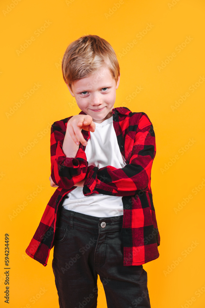 Stylish blond boy kid in a plaid shirt pointing with forefinger at camera Stylish blond boy kid in a plaid shirt pointing with forefinger at camera