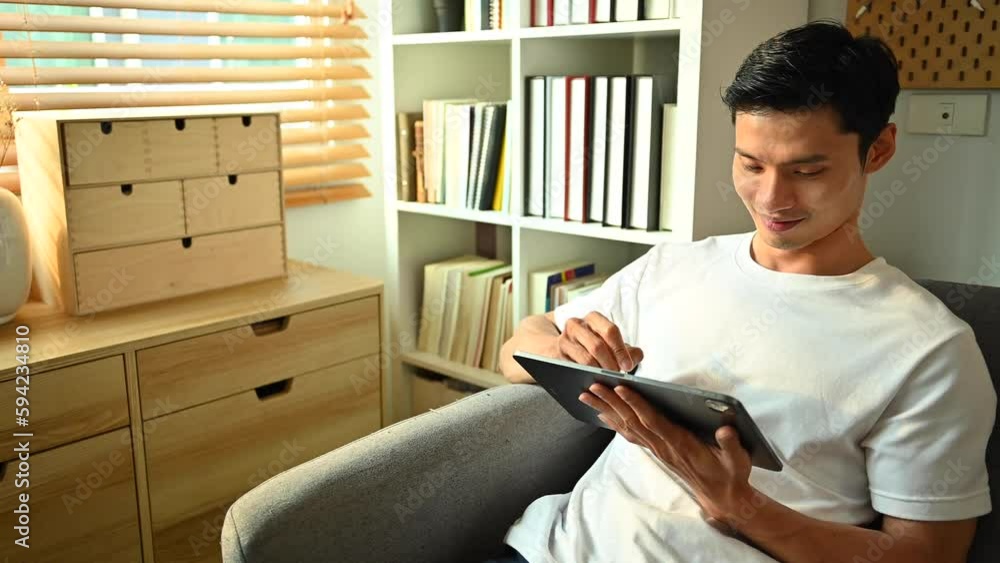 Happy adult asian man planning workday, checking schedule on digital tablet. People, technology and lifestyle concept Happy adult asian man planning workday, checking schedule on digital tablet. People, technology and lifestyle concept