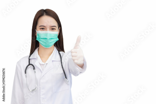 Asian professional woman doctor who wears medical coat and face mask shows thump up as “good” sign in health protection concept at hospital.