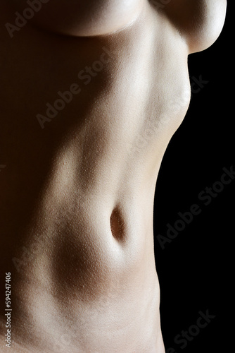 Close up of a perfekt female body in front of black background in studio