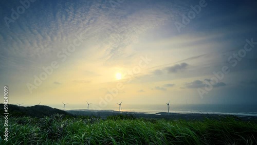 The windmill rotates to generate electricity, the beautiful sunset by the sea. Houlong the Cape, a famous tourist attraction. Miaoli County, Taiwan photo