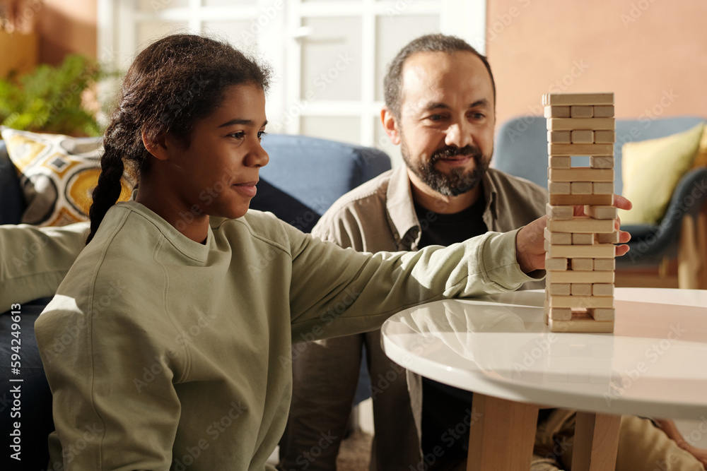 African American teenage girl playing board game with her foster dad at table in the living room African American teenage girl playing board game with her foster dad at table in the living room