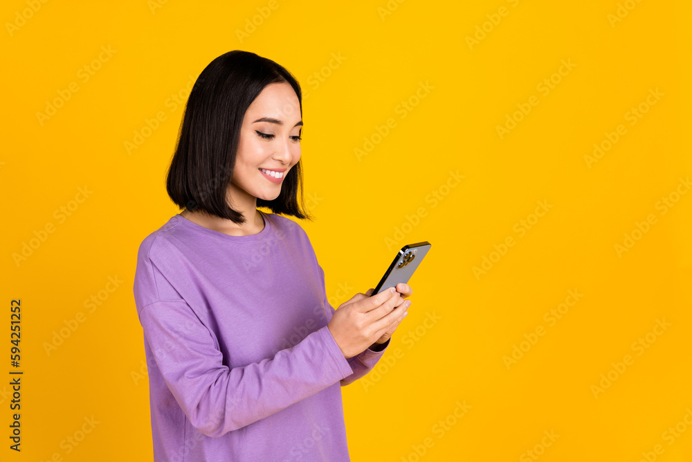 Photo of young chatting japanese girl wear violet shirt hold smartphone communicate networking online isolated on yellow color background Photo of young chatting japanese girl wear violet shirt hold smartphone communicate networking online isolated on yellow color background
