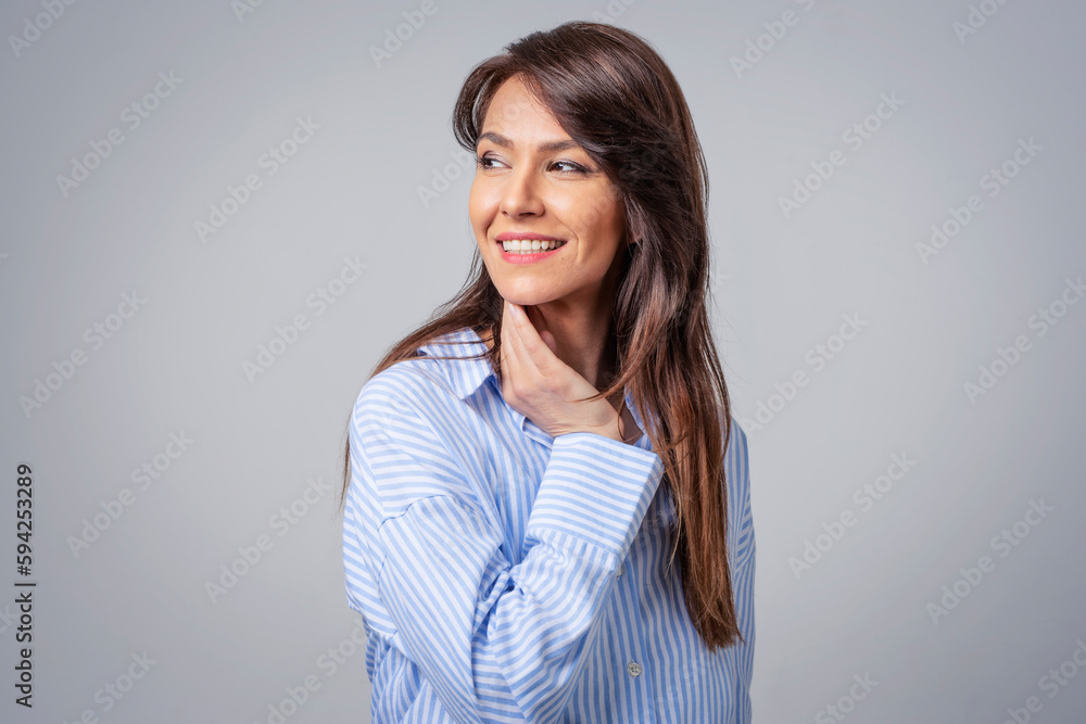 Studio portrait of attractive woman wearing shirt and laughing while sitting at isolated grey background. Studio portrait of attractive woman wearing shirt and laughing while sitting at isolated grey background.