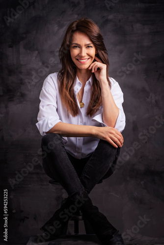 Smiling brunette businesswoman wearing white shirt and laughing against black background
