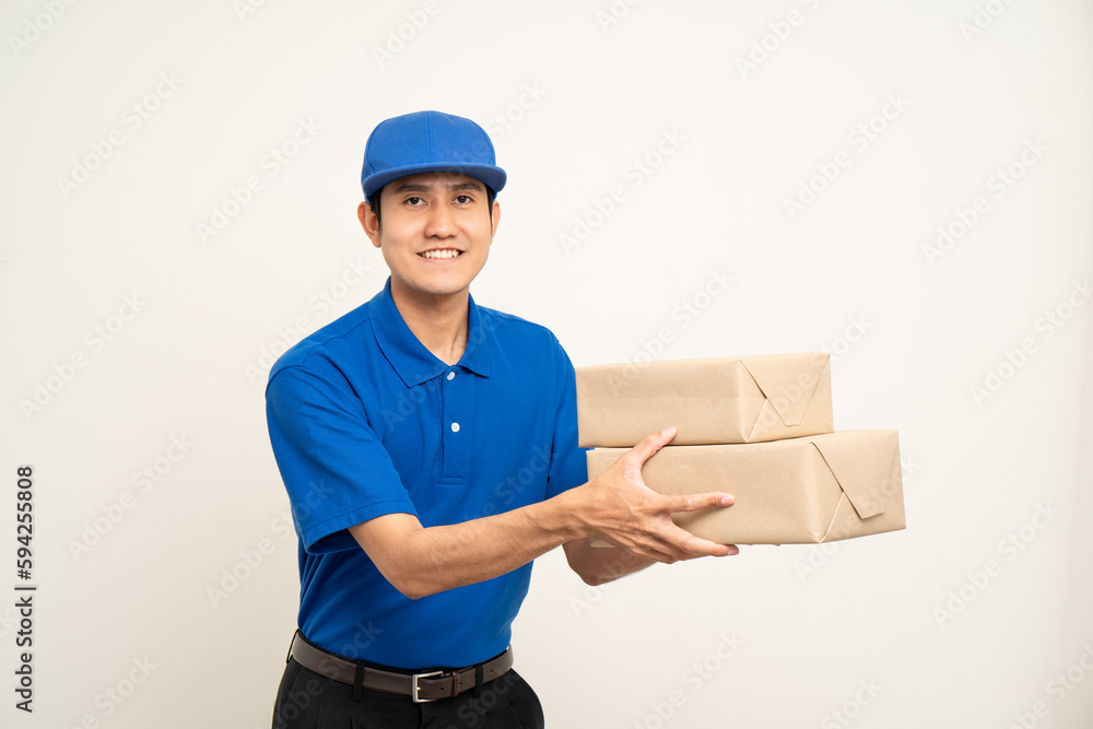 Asian man in blue uniform standing holding box parcel cardboard and smartphone on isolated white background. Male service worker with cell phone. Delivery courier shipping service Asian man in blue uniform standing holding box parcel cardboard and smartphone on isolated white background. Male service worker with cell phone. Delivery courier shipping service