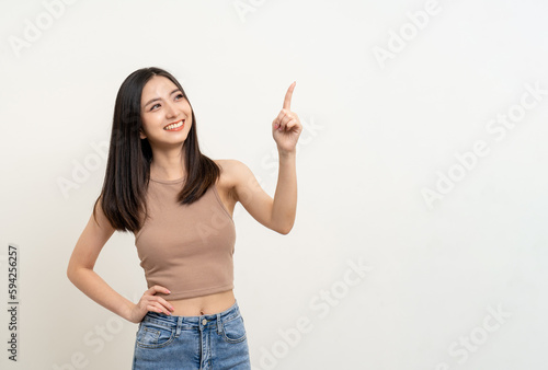 Happy beautiful young asian woman in brown shirt pointing finger to copy space. Smiling female lady with blank space. Asian cute Pretty people looking copy space text advertise