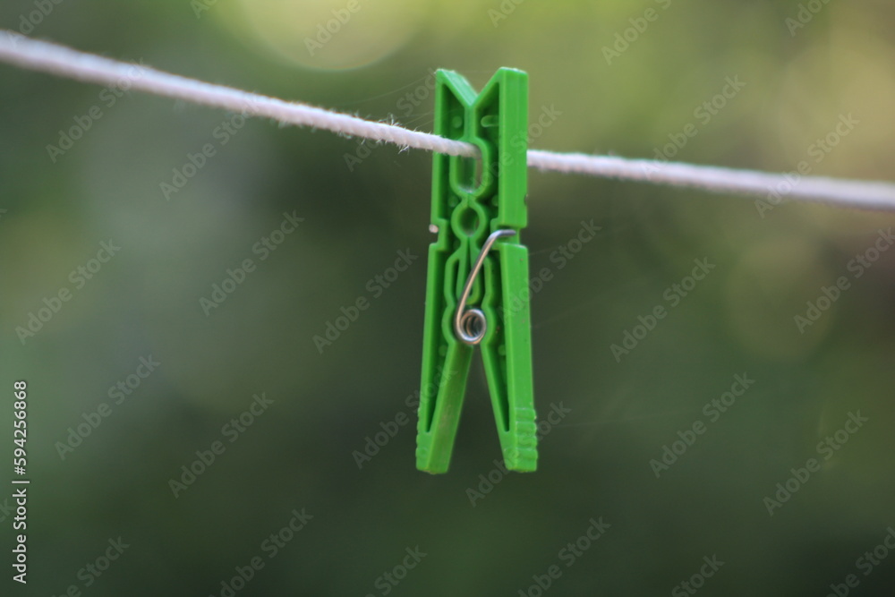 Green clothes peg on white clothesline blurred nature background. Green clothes peg on white clothesline blurred nature background.