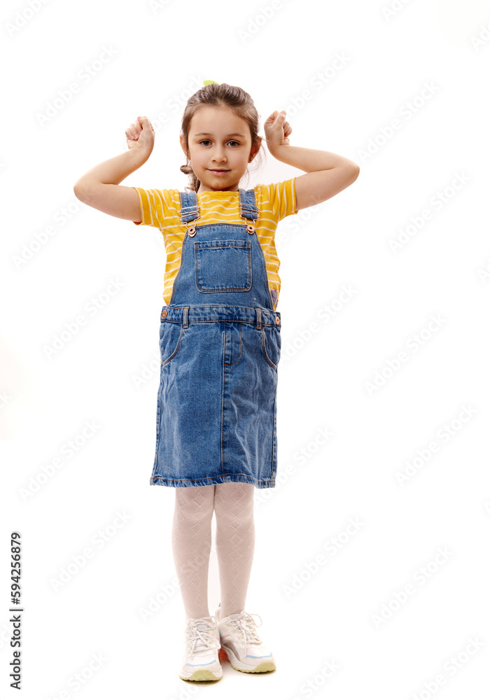Full length vertical portrait of Caucasian lovely little child girl gesturing, clenching fists, looking at camera, isolated over white background Full length vertical portrait of Caucasian lovely little child girl gesturing, clenching fists, looking at camera, isolated over white background