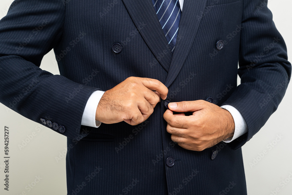 Obraz premium Confident businessman buttoning or adjust classic blue suit on isolated white background. Handsome man wearing a nice suit