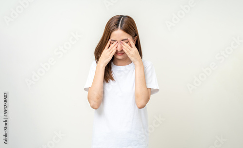 Fotografia Young asian beautiful woman hand rubbing eyes she's feeling depressed stress headache be tired from working standing on isolated white background she has health problems