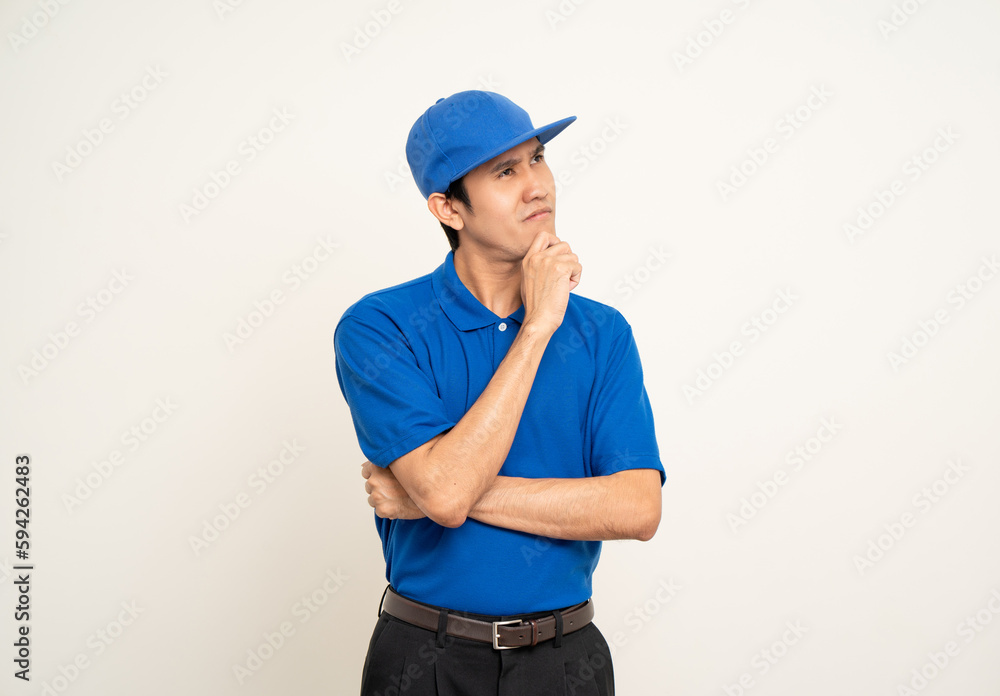 Happy delivery asian man in blue uniform standing thinking on isolated white background. Smiling male delivery service worker. Courier and shipping service. Happy delivery asian man in blue uniform standing thinking on isolated white background. Smiling male delivery service worker. Courier and shipping service.