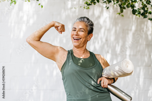Fotobehang Fit and proud: Senior woman flaunts her bicep as she celebrates her fitness achi