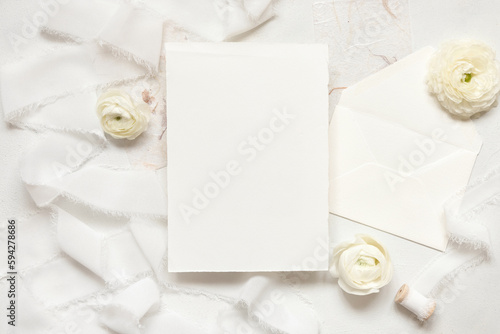 Blank card near cream roses and white silk ribbons, top view, wedding mockup