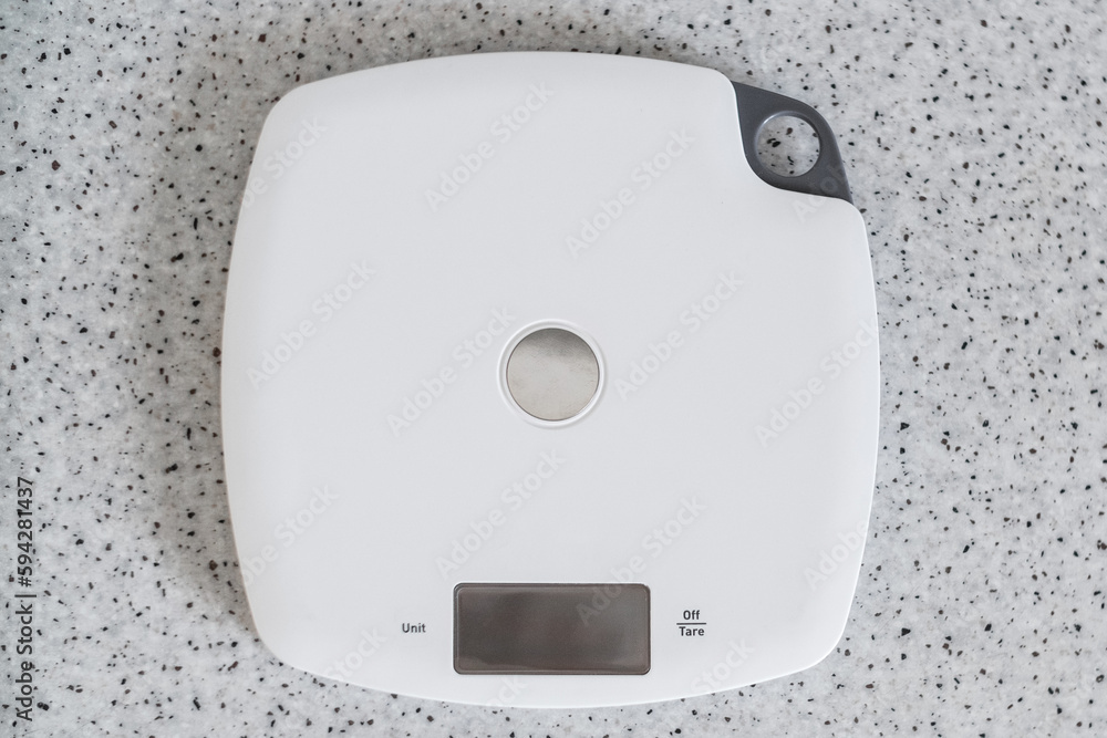 Digital kitchen scale on a kitchen table. Top view on electronic scales for measurement the food weight. Digital kitchen scale on a kitchen table. Top view on electronic scales for measurement the food weight.