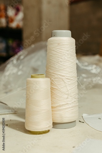 white thread spools sit on top of an all white table