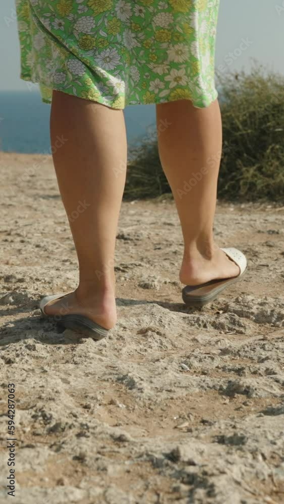A young woman in a green dress walks along the edge of a cliff, a cliff into the sea. Following. Vertical video Social Media A young woman in a green dress walks along the edge of a cliff, a cliff into the sea. Following. Vertical video Social Media