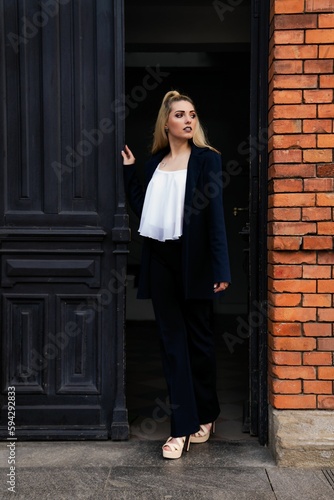 Professional female standing near the entrance of a building, looking off into the distance