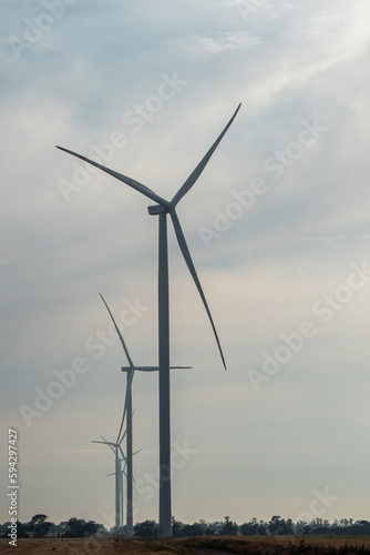 Line of windmills with rotating blades produce energy as renewable source for national economy. Generating of ecological form of energy on nasty day