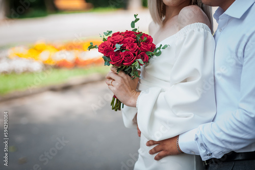 Fototapeta Naklejka Na Ścianę i Meble -  Bouquet of red roses in the hands of the bride. Bridal bouquet in woman's hands