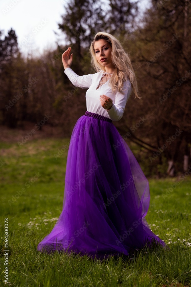 Young female posing in a white shirt and a purple tulle skirt in a park Young female posing in a white shirt and a purple tulle skirt in a park