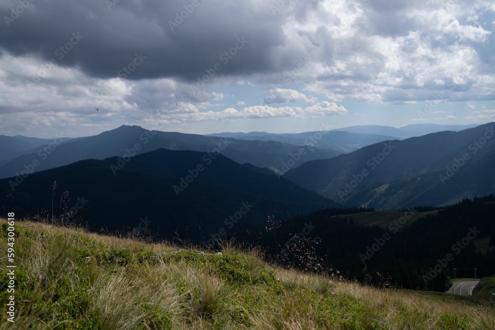 Obraz premium an open valley with tall grass on top and mountains in the distance