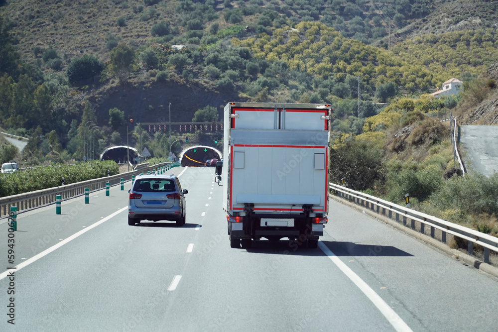 Truck on a highway - back view, tunnel through mountain Truck on a highway - back view, tunnel through mountain