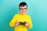 Photo of addicted boy playing video game with joy stick isolated on aquamarine color background