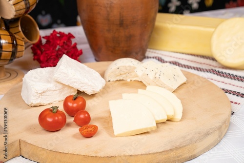 Closeup of a wooden tray with a variety of cheeses.