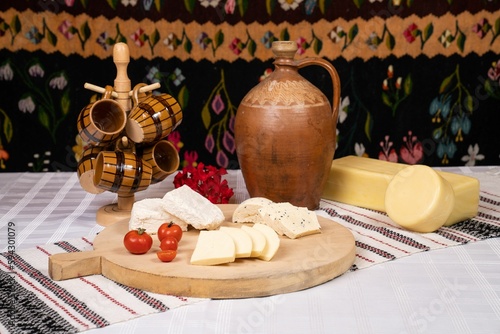 Rustic table with cut cheese, and tomatoes on the wooden board.