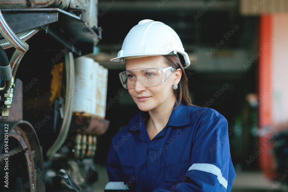 A female engineer wearing uniform with a white hat. Remote monitoring and control of robotic arm welding machines in industrial plants. A female engineer wearing uniform with a white hat. Remote monitoring and control of robotic arm welding machines in industrial plants.