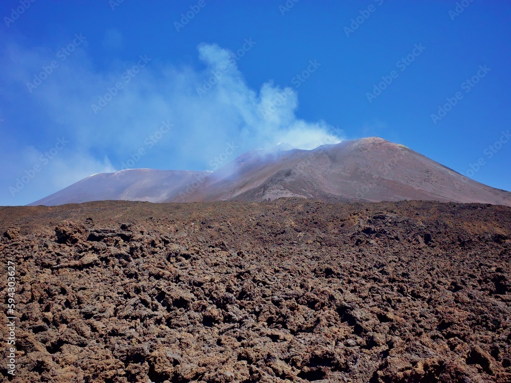 Stunning view of a barren, volcanic terrain with a smoky volcanic cloud in the background