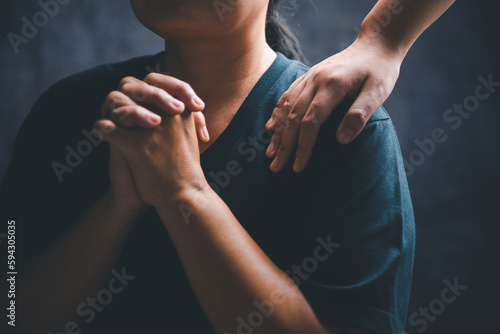 Woman laying hands on a young female christian shoulder to empower and bless him while he feels discouraged in a home office, Christian faith, and christians praying laying on hands concept.