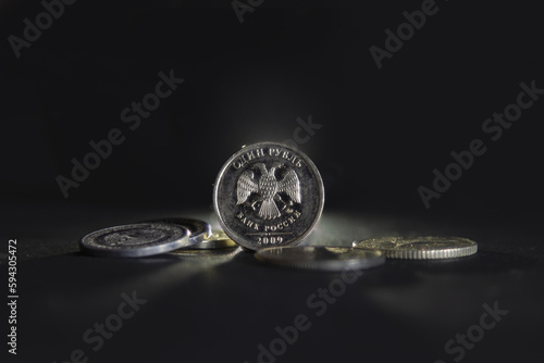 Selective blur on a one ruble coin with the mention one ruble and bank of russia written in russian, isolated on a black background. RUB, or russian ruble, is the official currency and money of Russia © Jerome