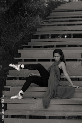 Obraz na płótnie black and white photo style, Ballerina in nature, Student woman practice ballet outdoor, sit at wooden stairs background. Health lifestyle image. w salonie