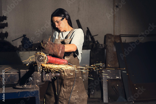 Focused female blacksmith cutting metal photo