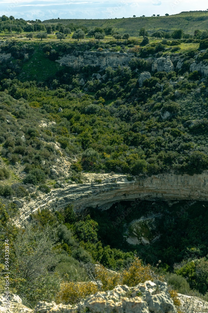Vertical of a large canyon, the Prastio dry waterfall surrounded by rich vegetation in Cyprus