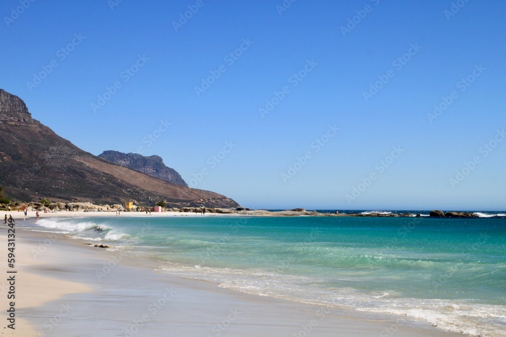 a beach scene with turquoise water and mountains in the distance