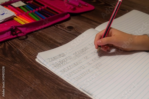 Young female student writing intently with a pencil at her desk photo