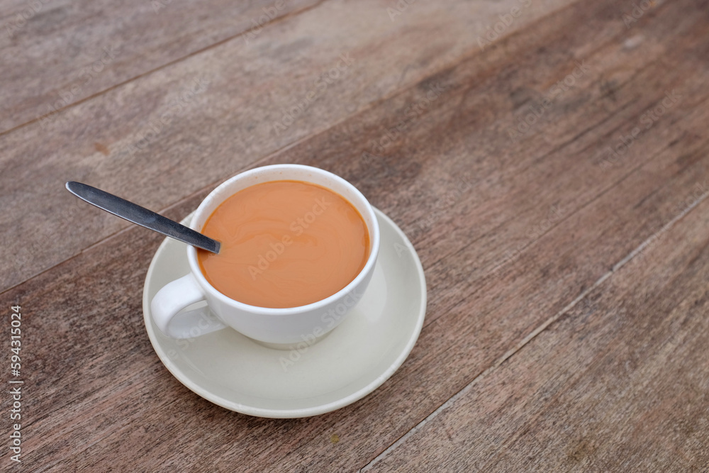 Obraz premium Tea with milk in porcelain cup on wood table background.