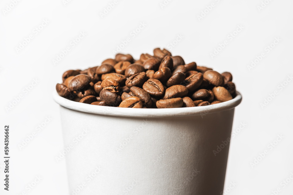 Paper cup filled with grains of fried coffee on white background. Paper cup filled with grains of fried coffee on white background.